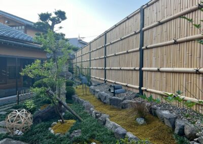 コンクリート塀に建仁寺垣を直接取り付け、庭の背景として自然に馴染む景色へ。